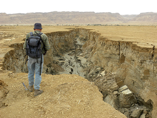 a man standing by an eroded land